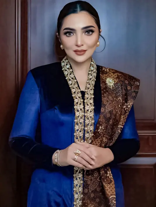 Ashanty tampil dengan kebaya biru navy panjang model velvet. Kebaya yang dibuat oleh Windy Savosa Couture ini memiliki bordiran di bagian depan. Melengkapi tampilannya dengan selendang batik senada dengan bawahan. Dan mengenakan bros di selendangnya. [@ashanty_ash].