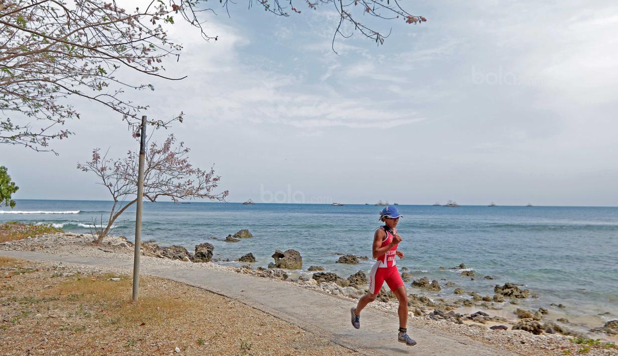 Seorang peserta wanita Rhino Cross Triathlon melintasi pemandangan pantai pada Festival Pesona Tanjung Lesung 2017 di Tanjung Lesung, Banten (24/9/2017). Total jarak tempuh Rhino Cross Triathlon 38 km. (Bola.com/Nicklas Hanoatubun)