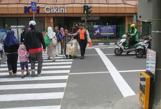Pejalan kaki melintasi penyeberangan pejalan kaki yang dikontrol lampu lalu lintas atau dikenal sebagai persimpangan pelikan (pelican crossing) di sisi timur Stasiun Cikini, Jakarta, Senin (15/9/2025). (merdeka.com/Arie Basuki)