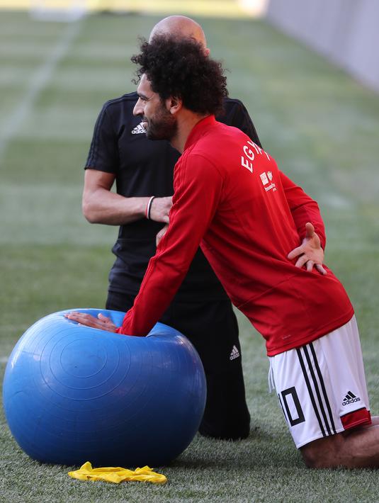 Pemain timnas Mesir Mohamed Salah bersama tim kesehatan melatih bahunya selama sesi pelatihan di stadion Akhmat Arena di Grozny (12/6). Meski masih dibekap cedera bahu, Salah tetap optimis dapat tampil di Piala Dunia 2018 Rusia. (AFP Photo/Karim Jaafar)