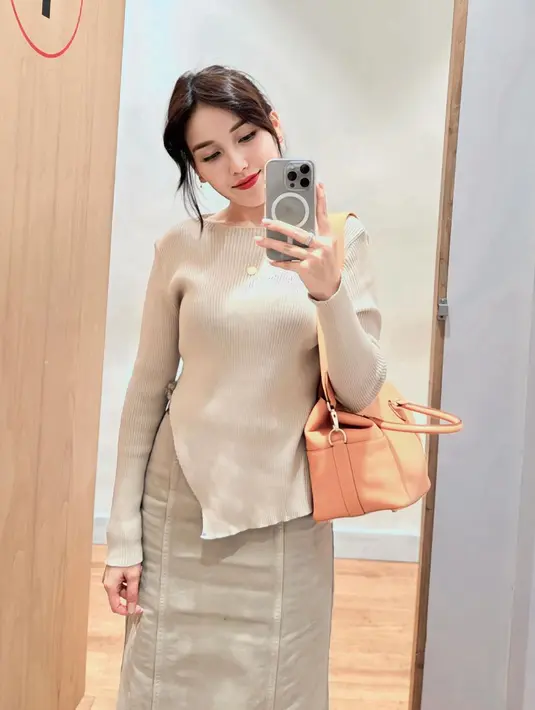 Gaya kasual cantik Ayu Ting Ting dengan outfit earth tone. Ia mengenakan atasan lengan panjang dengan bagian ujung yang asimetris, dipadu denim skirt yang sama-sama berwarna kecokelatan, serta membawa tas yang juga bernuansa senada. [Foto: Instagram/ayutingting92]