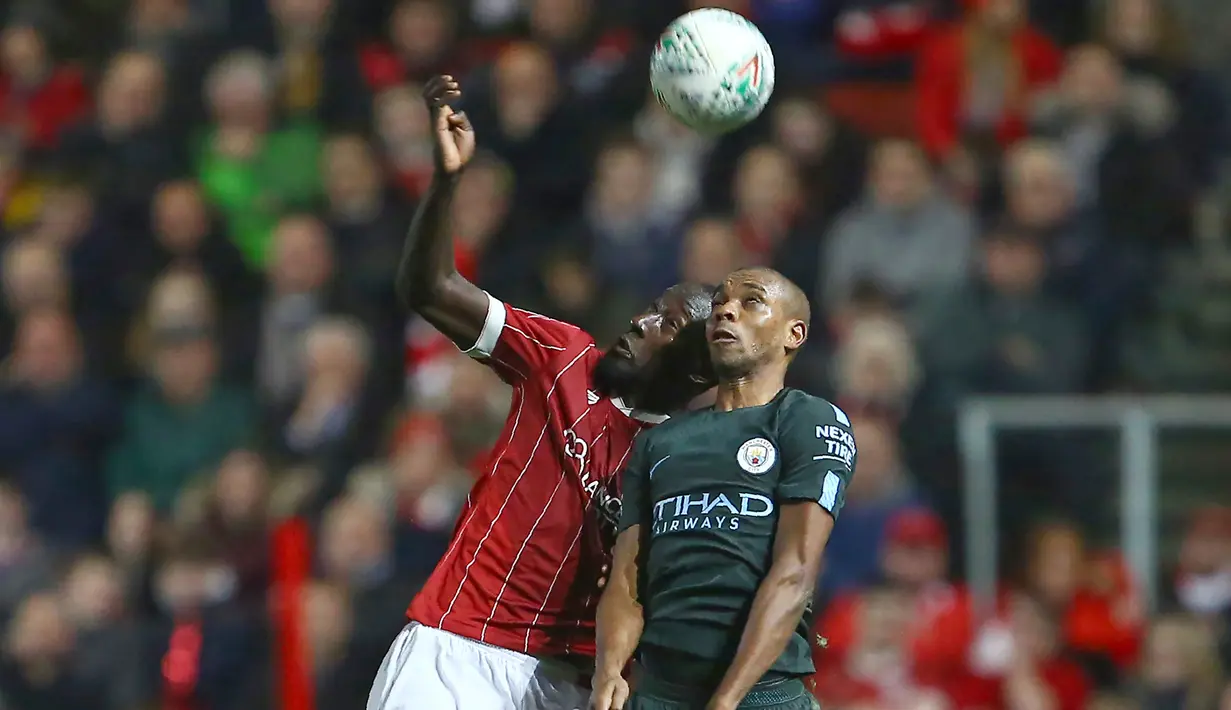 Duel pemain Bristol City, Famara Diedhiou (kiri) dan pemain Manchester City, Fernandinho pada semifinal Piala Liga Inggris di Ashton Gate stadium, Bristol,(23/1/2018). Manchester City menang 3-2. (AFP/Geoff Caddick)