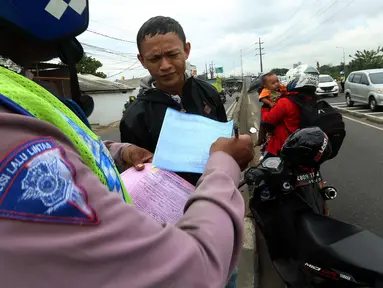 Petugas kepolisian memberi surat tilang ke pengendara saat Operasi Zebra Jaya 2017 di Daan Mogot, Jakarta, Selasa (7/11). Operasi Zebra yang digelar 1 November- 14 Desember 2017 tersebut secara serentak dilakukan se-Indonesia. (Liputan6.com/Johan Tallo)