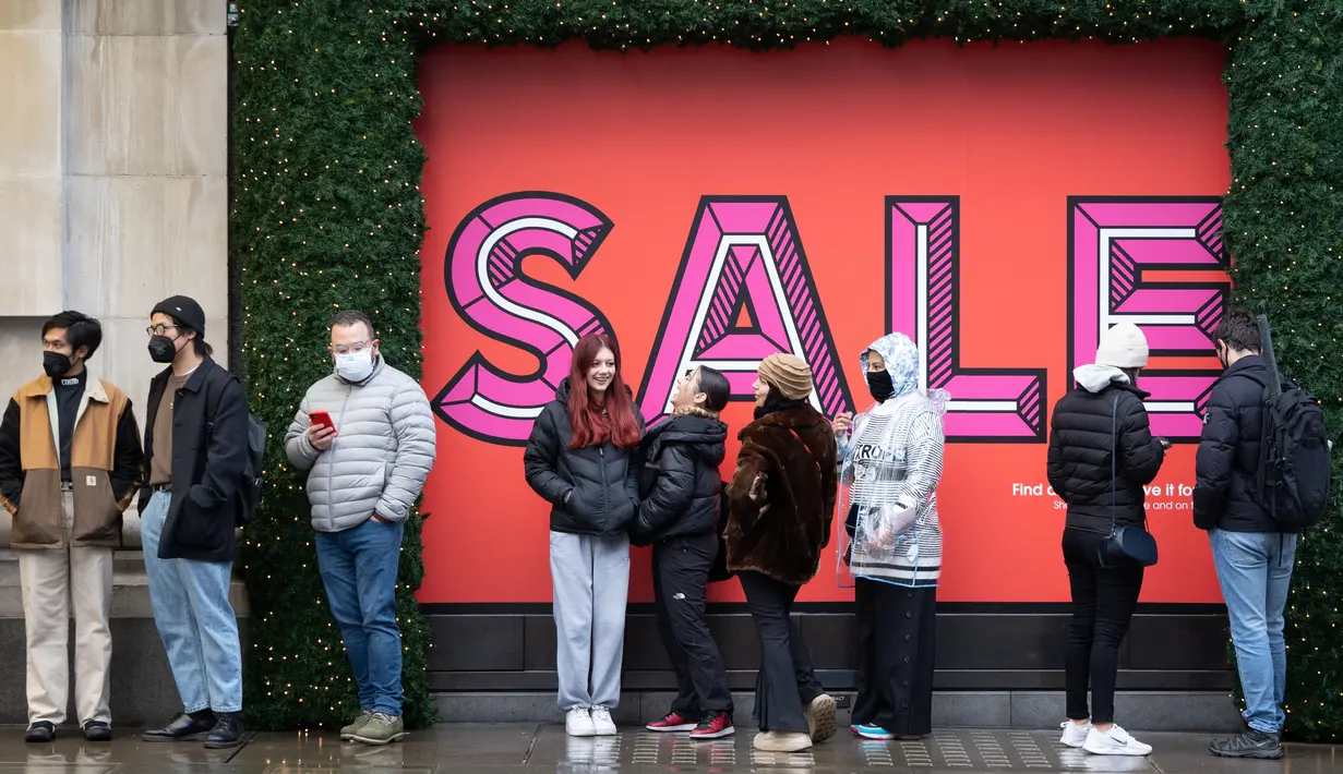 Pembeli, beberapa mengenakan masker, mengantre untuk memasuki department store Selfridges menjelang penjualan Boxing Day di pusat kota London, Minggu (26/12/2021).  'Boxing Day' adalah hari saat toko-toko di Inggris menggelar diskon besar-besaran, sehari setelah Natal. (Niklas HALLE'N / AFP)