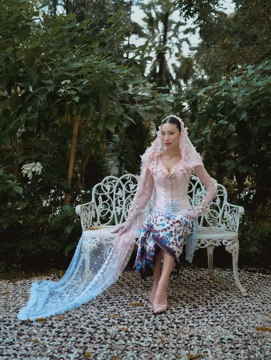 Siluet kebaya klasik yang fitted di tubuhnya dipadu dengan detail bordir halus dan aplikasi bunga tiga dimensi yang menjalar dari bahu hingga ujung lengan transparan.  [@patriciagouw].