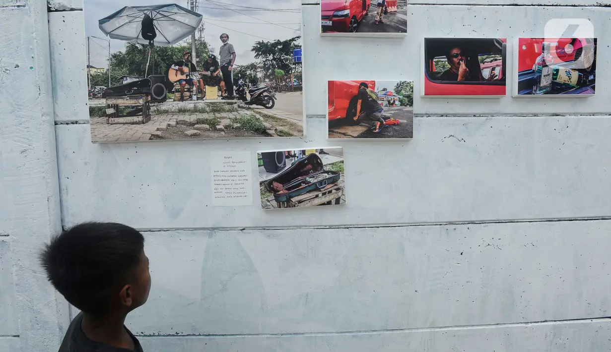 Seorang anak melihat karya foto selama kegiatan pameran Lensa Anak Terminal di Sekolah Master, Depok, Jawa Barat, Rabu  (8/2/2023). Pameran 170 karya foto dari 12 anak-anak terminal di kawasan tersebut merupakan hasil pembelajaran bersama Komunitas Lensa Anak Terminal dan berlangsung  hingga 12 Februari 2023. (merdeka.com/Arie Basuki)