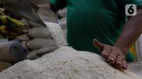 Pedagang memeriksa kondisi beras di pasar Cibubur, Jakarta, Senin (19/2/2024). (Liputan6.com/Herman Zakharia)