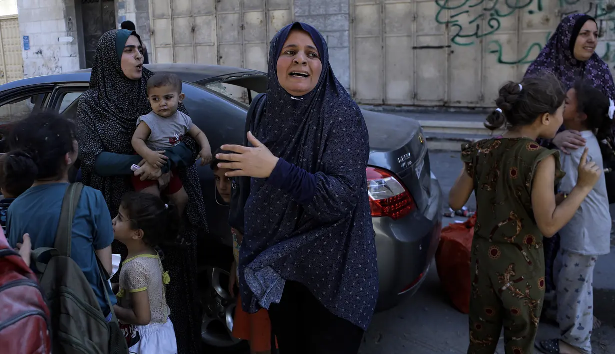 Warga Palestina dan beberapa anak-anak bergegas ke jalan menyusul serangan udara Israel di Kota Gaza, Jalur Gaza tengah, Minggu, 15 Oktober 2023. (AP Photo/Abed Khaled)