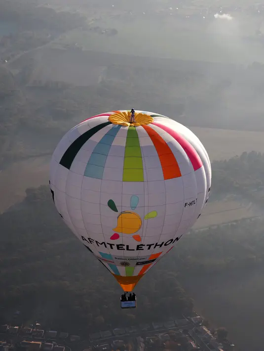 Balonist Prancis Remi Ouvrard mencoba memecahkan rekor dunia dengan berdiri di atas balon udara panas di Chatellerault, Rabu (10/11/2021). Ketinggian harus sama dengan nomor telepon kampanye Telethon 36-37, penggalangan dana tahunan Prancis untuk penelitian medis. (Guillaume SOUVANT/AFP)
