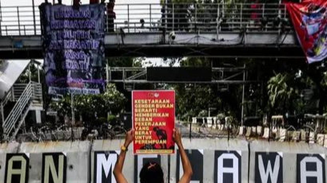 Seorang aktivis mengangkat poster saat berunjuk rasa memperingati Hari Perempuan Internasional di kawasan Patung Kuda, Jakarta, Jumat (8/4/2024). Liputan6.com/Angga Yuniar