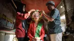 Seorang perempuan dengan pakaian tradisional dibantu menyiapkan hiasan bunga di rambutnya untuk berpartisipasi dalam Festival Ngarot di Lelea, Indramayu , Jawa Barat, pada 13 Desember 2023. (Timur MATAHARI/AFP)