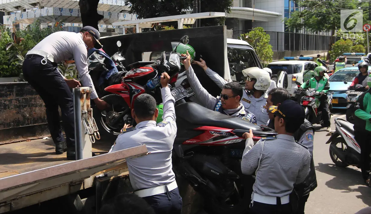 Petugas Dishub DKI Jakarta mengangkut motor saat razia parkir liar di Jalan KH Wahid Hasyim, Jakarta, Rabu (4/4). Dishub DKI Jakarta menertibkan pengendara ojek online yang memarkirkan kendaraan sembarangan di pinggir jalan. (Liputan6.com/Arya Manggala)