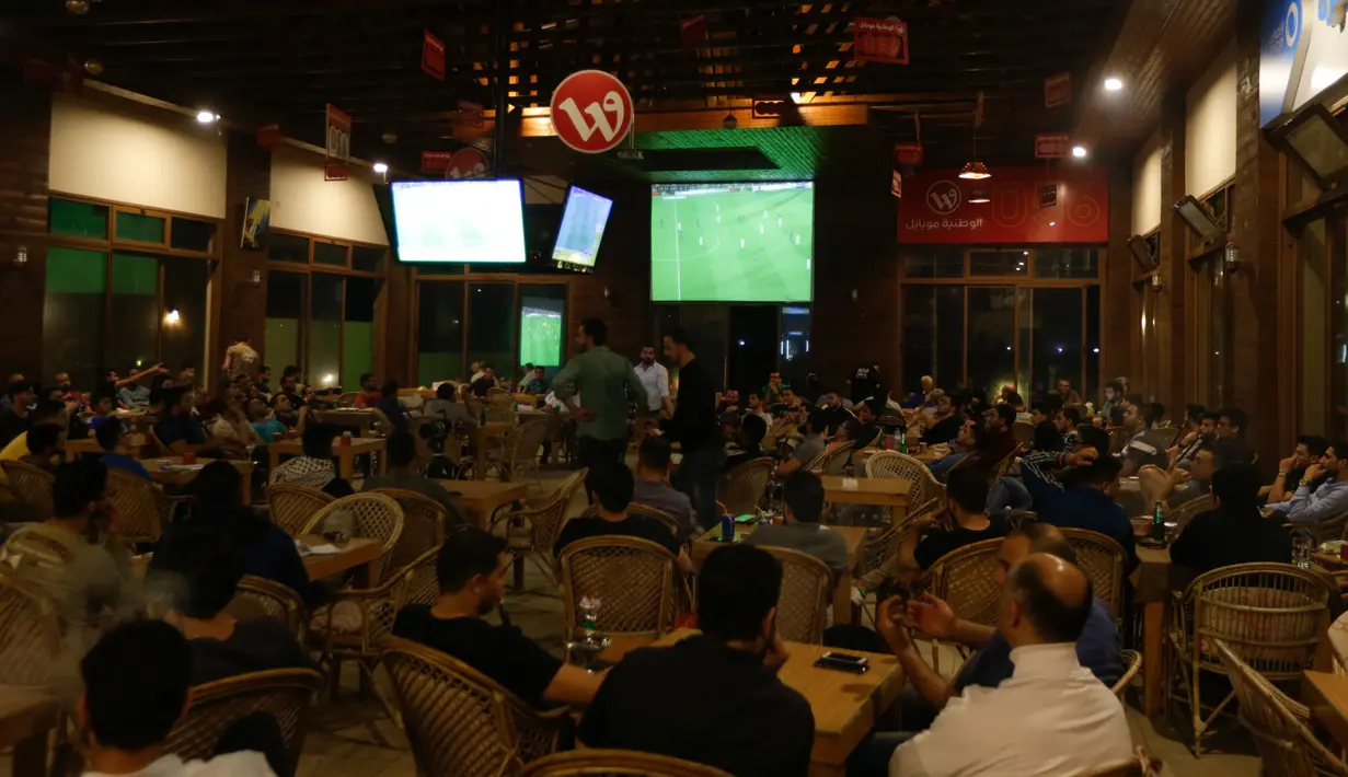 Warga Palestina menyaksikan pertandingan sepak bola Clasico antara Real Madrid dan Barcelona FC di sebuah kafe di Kota Gaza (6/5). Sebelum pertandingan ini, Barcelona telah memastikan gelar juara La Liga yang ke 25. (AFP Photo/Mahmud Hams)