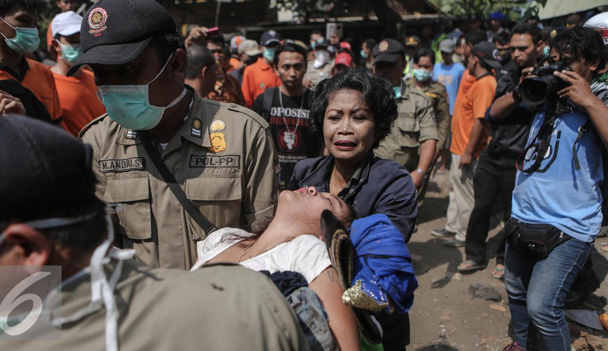 Seorang warga terlihat pingsan usai menyaksikan petugas merobohkan bangunan tempat tinggalnya saat penggusuran terjadi di Rawasari Selatan, Jakarta, Kamis (23/7/2015). Tampak upaya petugas mengevakuasi warga yang pingsan. (Liputan6.com/Faizal Fanani)
