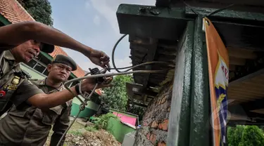 Petugas PLN dibantu petugas Kecamatan Johar Baru memutus kabel saluran listrik ilegal di Johar Baru, Jakarta Pusat, Rabu (25/3/2015). Kegiatan itu untuk mengurangi saluran listrik ilegal dan mencegah kebakaran.   (Liputan6.com/Faizal Fanani)