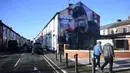 Pejalan kaki berjalan melewati mural karya seniman Hugh Whitaker dari MurWalls bergambar manajer Liverpool, Jurgen Klopp di dekat Anfield, Liverpool, barat laut Inggris, pada 26 Januari 2024. (Paul ELLIS/AFP)