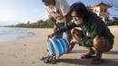 Seorang sukarelawan melepaskan bayi penyu ke laut di Bali, Indonesia, Selasa (6/7/2021). Puluhan penyu Lekang yang baru menetas dilepasliarkan dalam kampanye penyelamatan penyu yang terancam punah. (AP Photo/Firdia Lisnawati)