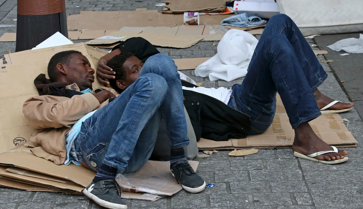 Dua orang imigran berbaring menggunakan kardus bekas sebagai alas di sebuah kamp darurat di jalanan Kota Paris, Prancis, Selasa (6/9). Para imigran berkulit hitam tersebut hidup terlantar di pinggir jalan kota tersebut. (REUTERS/Benoit Tessier)