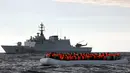 Perahu karet yang mengangkut para imigran Afrika terlihat di samping kapal angkatan laut Italia di Laut Meditarania, sekitar 36 mil laut dari lepas pantai Libya (2/2). (Reuters/Yannis Behrakis)