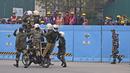 Pekerja menyaksikan pasukan pertahanan berlatih untuk parade Hari Republik mendatang di perbukitan Raisina, pusat kekuasaan pemerintah, di New Delhi, India (17/1/2022). India akan merayakan Hari Republik pada 26 Januari. (AP Photo/Manish Swarup)