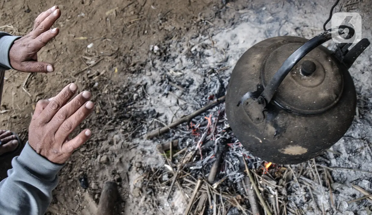 Seorang anggota Jekpass menghangatkan diri di dekat api unggun sekaligus tungku masak air saat menunggu pendaki yang turun dari Gunung Sindoro, Wonosobo, Senin (13/9/2021). Anggota Jekpass berharap wisata pendakian tetap dibuka meski masih di tengah Covid-19. (merdeka.com/Iqbal S Nugroho)