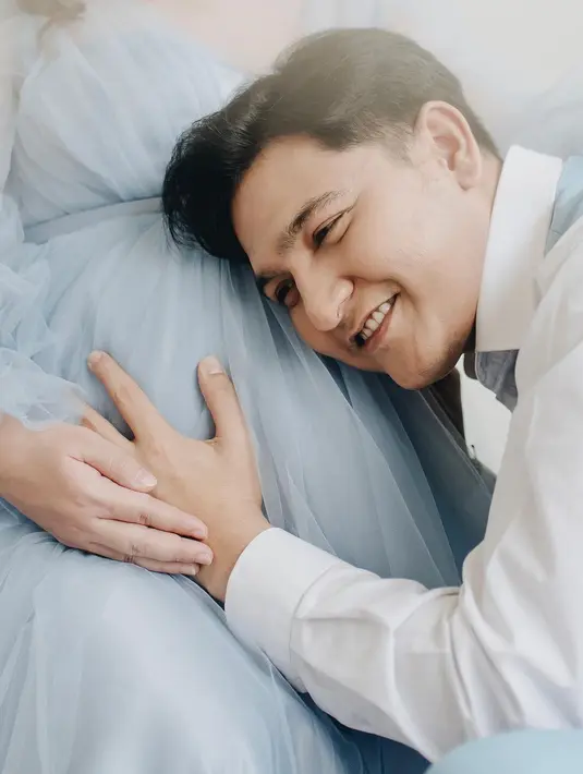 Pose manis calon ayah menempelkan telinga ke perut sang istri yang makin besar. Masayu sedang hamil anak kembar. [Instagram/masayuclara]