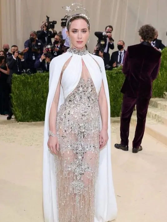Emily Blunt membawa energi All-america ke dalam Met Gala 2021 dengan balutan dress bertabur kristal rancangan Miu Miu. Jubah putih dan headpiece berhiaskan bintang yang ia kenakan pun menambah kesan elegan bak dewi Aphrodite pada penampilannya. (Instagram/weddingbyjess)
