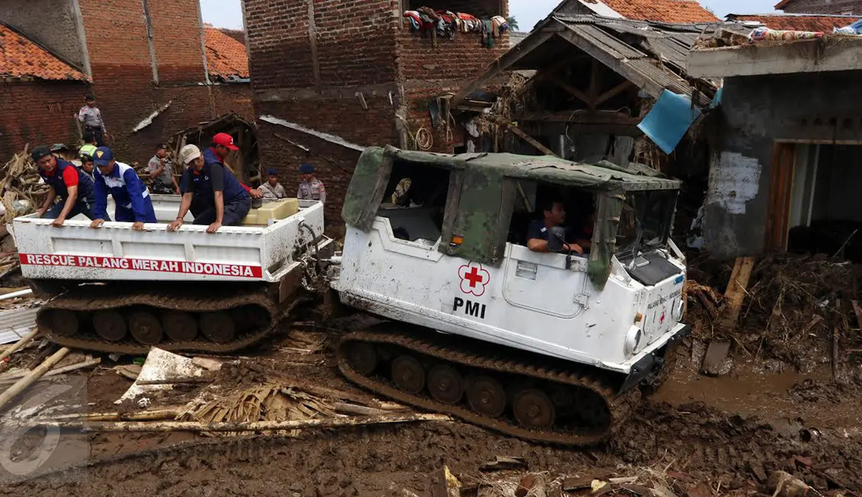Sukarelawan PMI menaiki kendaran hagglund di Kampung Bojong Sudika, Cimacan, Garut, Jumat (23/9). PMI mengerahkan kendaraan Hagglund untuk membantu proses evakuasi di tengah kawasan yang penuh lumpur akibat banjir bandang. (Liputan6.com/Johan Tallo)