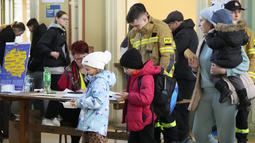 Anak-anak dari Ukraina menerima sup di stasiun kereta api di Przemysl, Polandia tenggara, pada Rabu (23/3/2022). Polandia telah menerima lebih dari 2 juta pengungsi Ukraina sejak invasi Rusia pada 24 Februari lalu. (AP Photo/Sergei Grits)
