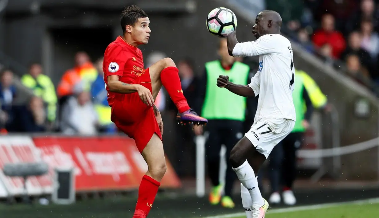 Pemain Liverpool, Philippe Coutinho (kiri), berebut bola dengan pemain Swansea City, Modou Barrow, dalam laga Premier League, di Liberty Stadium, Sabtu (1/10/2016). (Reuters/Stefan Wermuth)