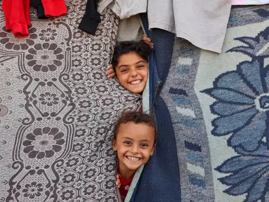 Anak-anak bermain di sebuah tenda darurat untuk warga Palestina yang mengungsi dari Gaza utara, di stadion Yarmouk yang rusak di Kota Gaza pada 14 Oktober 2024. (Omar AL-QATTAA/AFP)