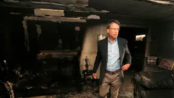 Gubernur North Carolina Pat McCrory meninjau kerusakan yang disebabkan serangan bom di Kantor Partai Republik, Orange County, Senin (17/10). Dinding bagian dalam gedung itu terlihat menghitam akibat kebakaran yang dipicu bom molotov. (REUTERS/Chris Keane)