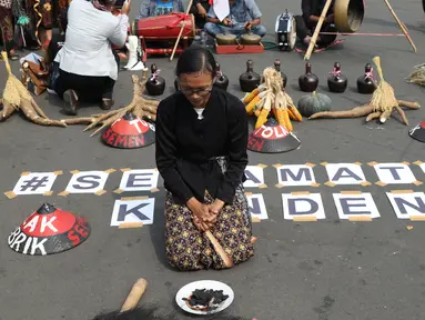 Salah satu petani Kendeng terduduk saat aksi di depan Istana Negara, Jakarta, Kamis (2/8). Dalam aksinya, petani Kendeng melakukan tradisi Brokohan atau makan bersama nasi aneka urap yang sebelumnya didoakan. (Liputan6.com/Helmi Fithriansyah)
