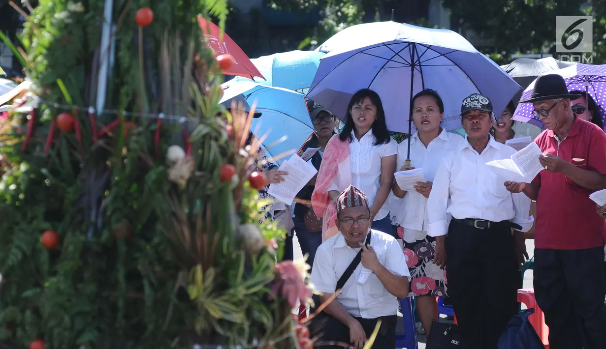 Jemaat GKI Yasmin dan HKBP Filadelfia berdoa pada misa Natal 2017 di Silang Barat Laut atau seberang Istana Merdeka, Jakarta, Senin (25/12). Kebaktian dilangsungkan sebagai bentuk protes terhadap hak kebebasan beribadah. (Liputan6.com/Helmi Fithriansyah)
