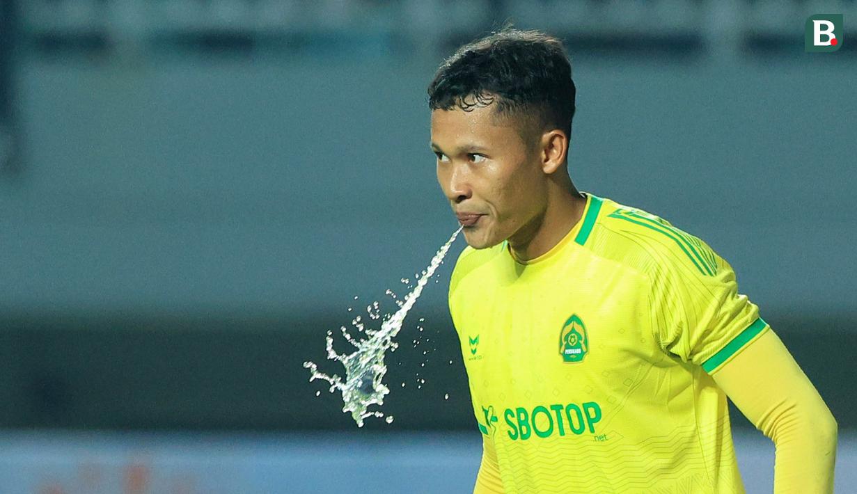 Kiper Persikabo 1973, Syahrul Trisna menyemprotkan air dari dalam mulutnya pada laga pekan kedua BRI Liga 1 2023/2024 melawan Persija Jakarta di Stadion Pakansari, Cibinong, Bogor, Minggu (9/7/2023). (Bola.com/M Iqbal Ichsan)