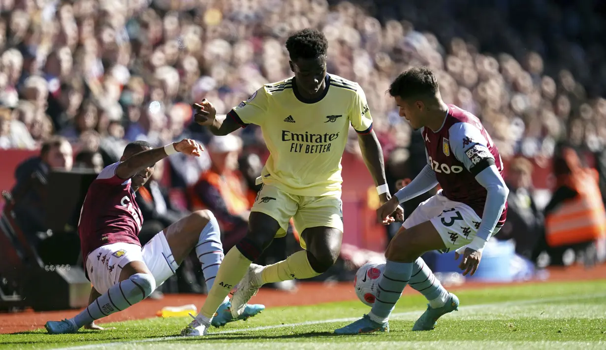 Pemain Aston Villa, Ashley Young dan Philippe Coutinho berusaha merebut bola dari gelandang Arsenal, Bukayo Saka pada pertandingan lanjutan Liga Inggris di Villa Park, Birmingham, Inggris, Sabtu (19/3/2022). Dengan hasil ini, Arsenal berada di peringkat keempat dengan 54 poin. (Nick Potts/PA via AP)