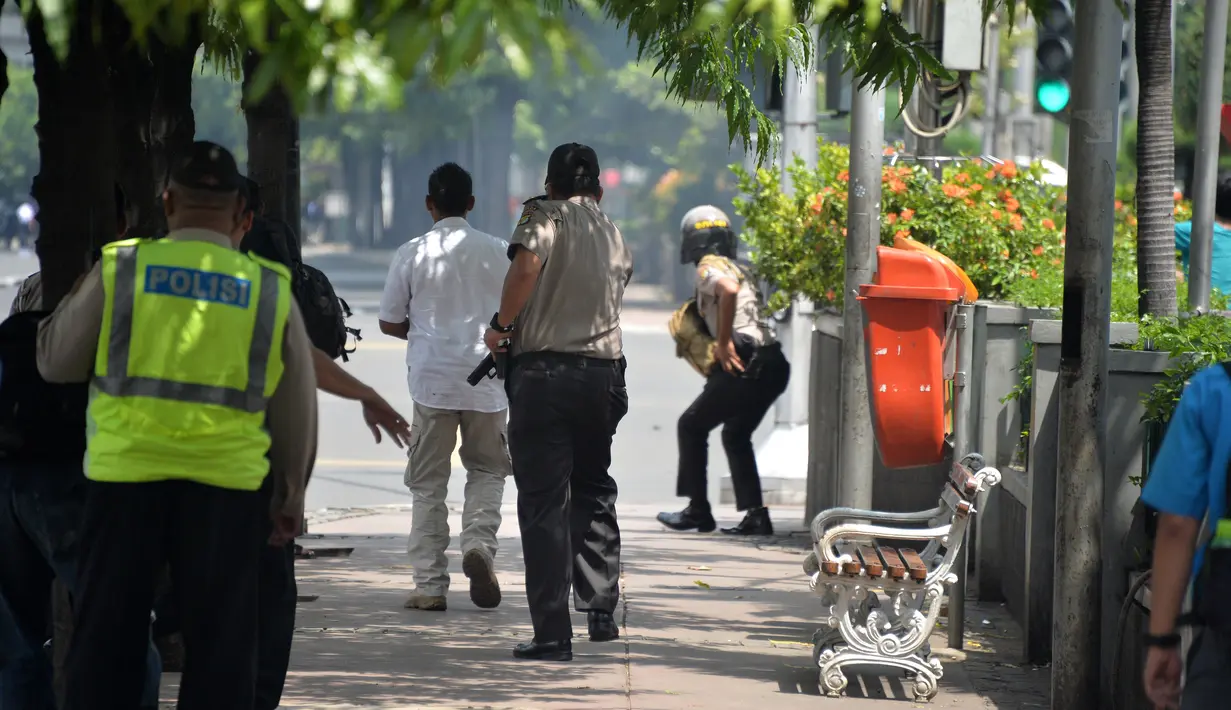 Polisi mengejar pelaku yang diduga bersembunyi di dalam sebuah kafe pasca ledakan di pospol Sarinah, Jakarta, Kamis (14/1). Baku tembak terjadi di depan Sarinah setelah suara ledakan ketiga terjadi.  (AFP PHOTO/Bay Ismoyo)