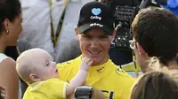 Chris Froome menggendong anaknya seusai menjuarai Tour de France 2016, Minggu (24/7/2016). (BBC)