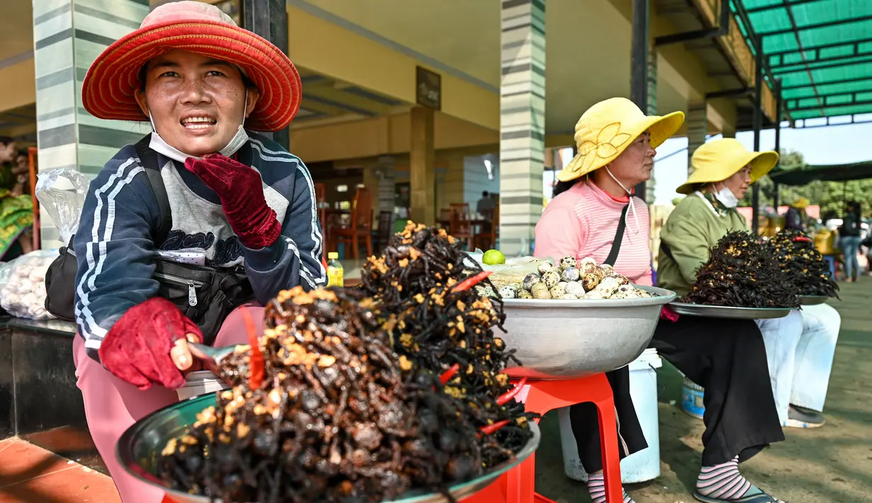 <p>Pedagang Kamboja membawa tarantula goreng dan jangkrik di kota Skun di provinsi Kampong Cham pada 15 Januari 2023. Ternyata sajian tarantula ini sudah populer sejak tahun 70-an dikarenakan masyarakat Skun mengalami krisis pangan. (Photo by TANG CHHIN SOTHY / AFP)</p>