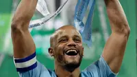 Bek Manchester City Vincent Kompany mengangkat trofi setelah memenangkan pertandingan final Piala Liga Inggris melawan Chelsea di stadion Wembley, London, Minggu (24/2). Manchester City Chelsea lewat drama adu penalti 4-3. (AP/ Tim Ireland)