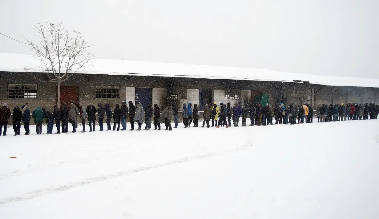 Demi semangkuk makanan, mereka harus rela mewalan "ganasnya" badai salju di kamp pengungsian di Belgrade, Serbia (11/1). (AP Photo/Darko Vojinovic)