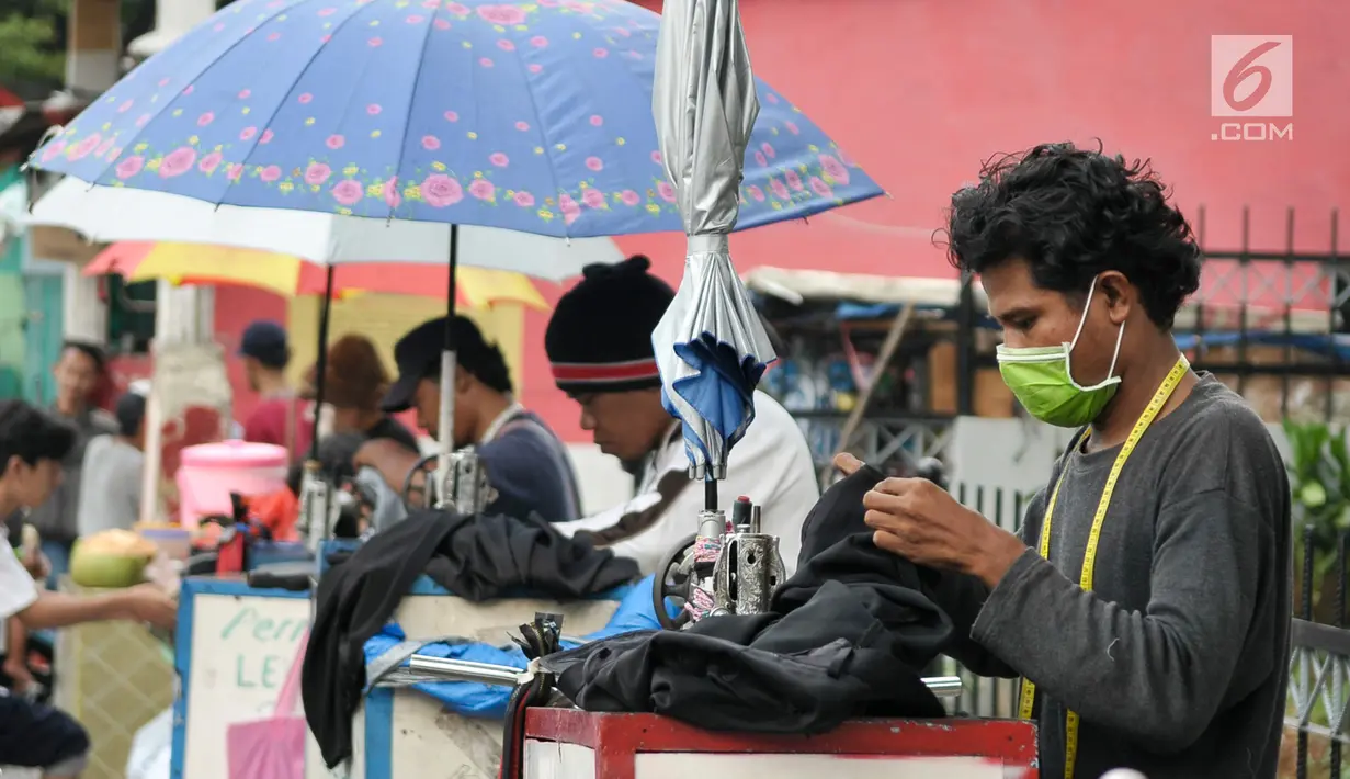 Sejumlah penjahit keliling saat menerima orderan pelanggan, Jakarta, Kamis (22/6). Para penjahit yang biasanya berkeliling masuk kampung ini lebih memilih untuk mangkal di saat jelang lebaran. (Liputan6.com/Yoppy Renato)