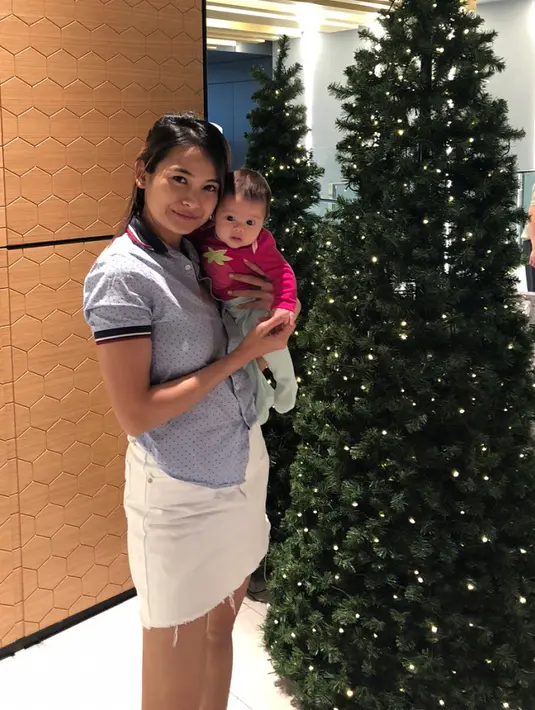 Seperti ini misalnya, Acha sungguh menggemaskan dengan mini skirt putih dan polo shirtnya. Ia menggendong Bridgia di depan pohon Natal, dan anaknya yang menggemaskan itu tampil dengan baju berwarna pinknya. (Instagram/septriasaacha)