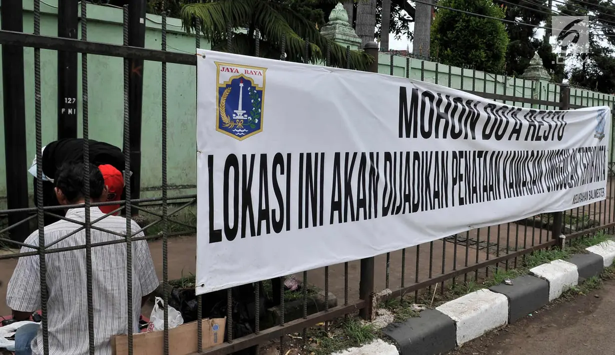 Pedagang menjajakan dagangannya di dekat spanduk bertuliskan "Mohon Doa Restu, Lokasi ini akan Dijadikan Kawasan Unggulan Tertib Kota" yang terpampang di sekitar Jatinegara, Jakarta Timur, Rabu (21/3). (Merdeka.com/Iqbal S. Nugroho)
