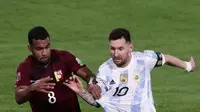 Pemain Argentina Lionel Messi (kanan) dan pemain Venezuela Yangel Herrera berebut bola pada pertandingan sepak bola kualifikasi Piala Dunia 2022 di Stadion La Bombonera, Buenos Aires, Argentina, 25 Maret 2022. Argentina menang 3-0. (ALEJANDRO PAGNI/AFP)