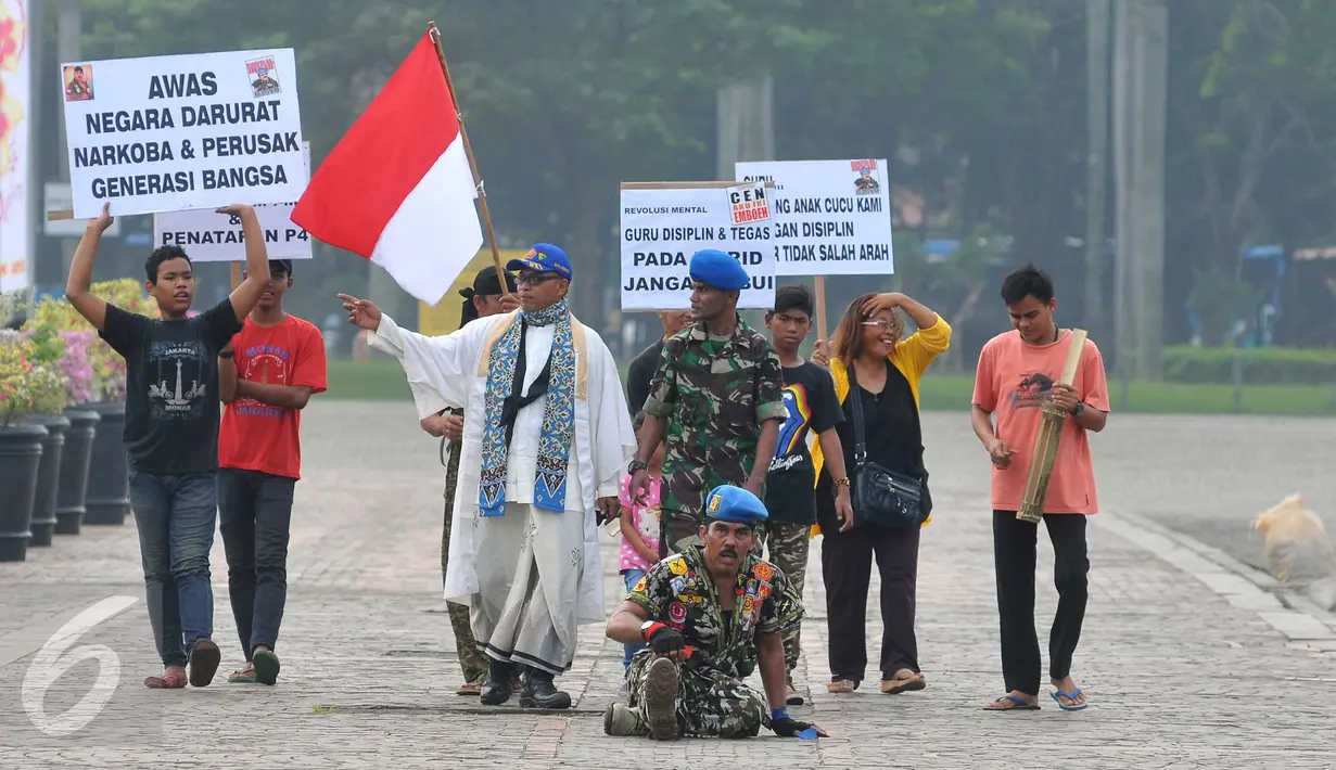 Aksi Anggota Polisi Militer Angkatan Darat IV/Surakarta Kopral Partika Subagyo Lelono (53) di Tugu Monas, Jakarta, Jumat (17/6). Kopral Bagyo juga didampingi beberapa orang sambil membawa atribut bertulisan bahaya narkoba. (Liputan6.com/Gempur M Surya)