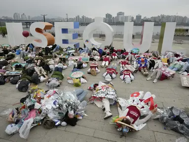 Aktivis lingkungan mengenakan pakaian yang terbuat dari sampah plastik berbaring di tanah selama kampanye untuk memperingati Hari Bumi melawan perubahan iklim di Seoul, Korea Selatan, Jumat (22/4/2022). (AP Photo/Ahn Young-joon)