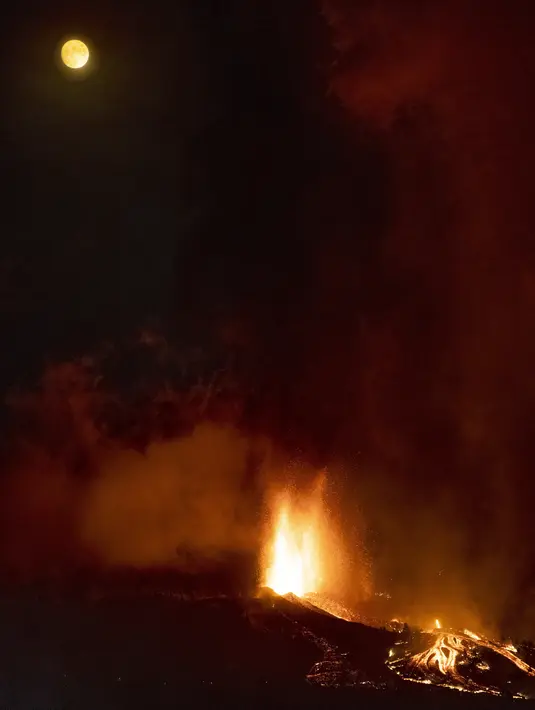 Lava dan asap mengalir dari letusan gunung berapi di pulau La Palma di Kepulauan Canaria, Spanyol, Minggu (19/9/2021). Letusan gunung berapi itu memuntahkan lava, debu, dan asap besar. (AP Photo/Jonathan Rodriguez)