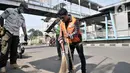 Seorang warga membersihkan jalanan saat menjalani hukuman sosial pelanggar PSBB di area Pasar Kramat Jati, Jakarta, Rabu (17/6/2020). (merdeka.com/Iqbal S. Nugroho)