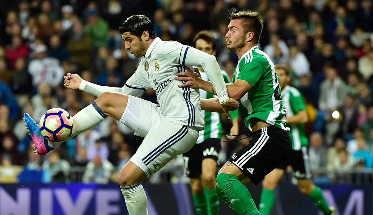 Penyerang Real Madrid, Alvaro Morata berusaha mengontrol bola dari kawalan gelandang Real Betis, Alin Tosca pada lanjutan La Liga Spanyol di Stadion Bernabeu, Madrid, (13/3). Real Madrid menang atas Real Betis dengan skor 2-1. (AFP Photo / Gerard Julien)